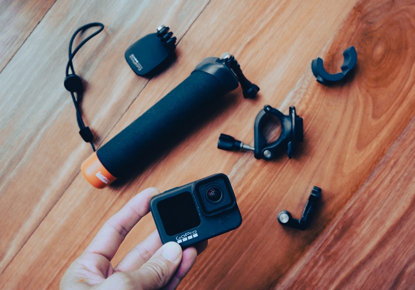 a person holding a gopro camera next to various accessories.
