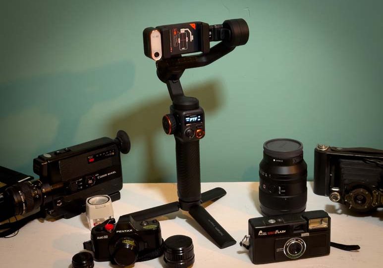 A group of cameras, tripods, and other equipment on a table.
