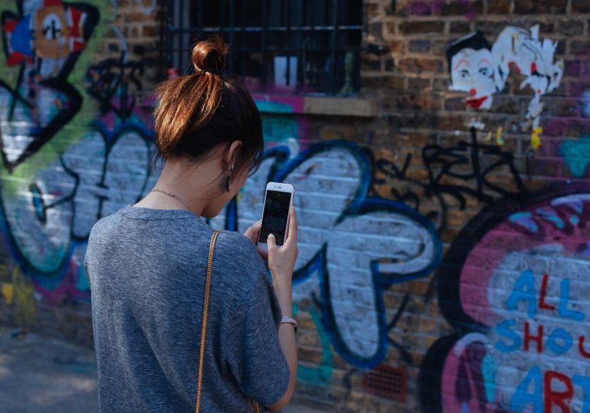 A woman is taking a picture of graffiti on a wall.