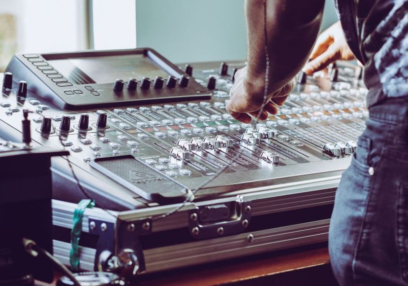 A man is working on a mixing board in a recording studio.