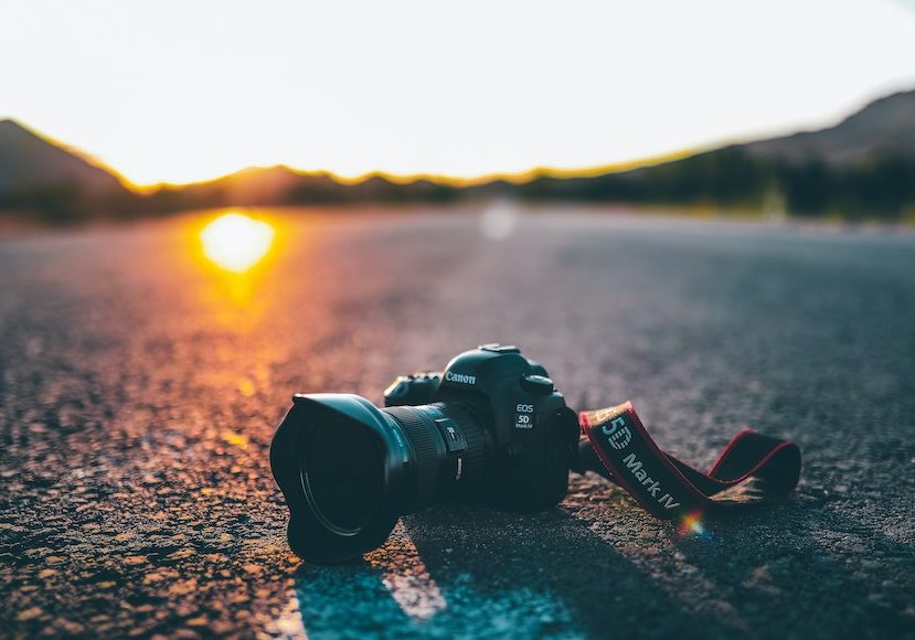 A dslr camera lying on the road at sunset.