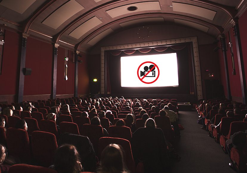 a movie theater with a large screen and red chairs.