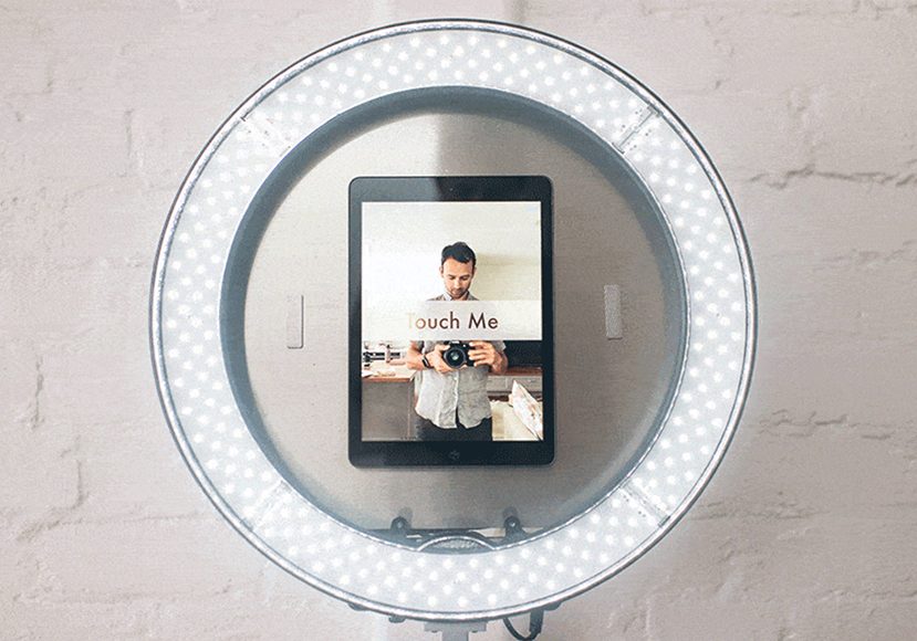 A lighted mirror with a tablet on it.