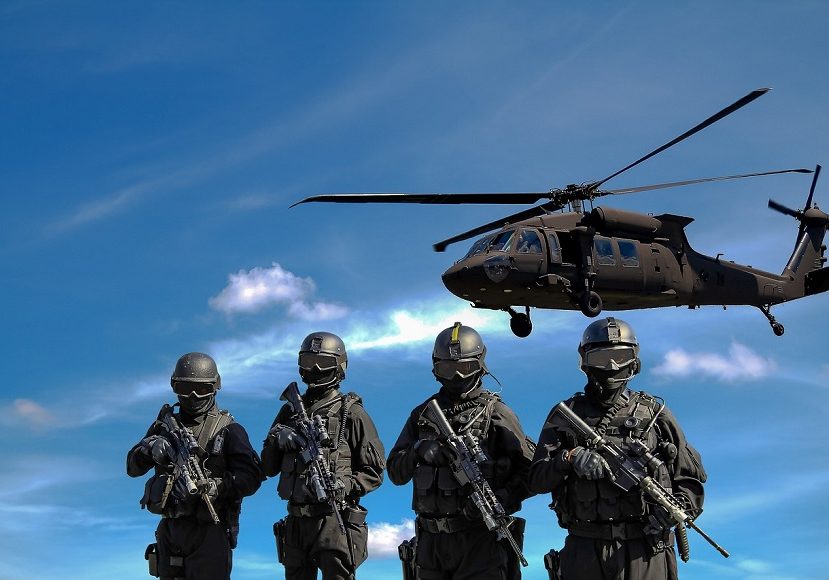 A group of soldiers standing in front of a helicopter.