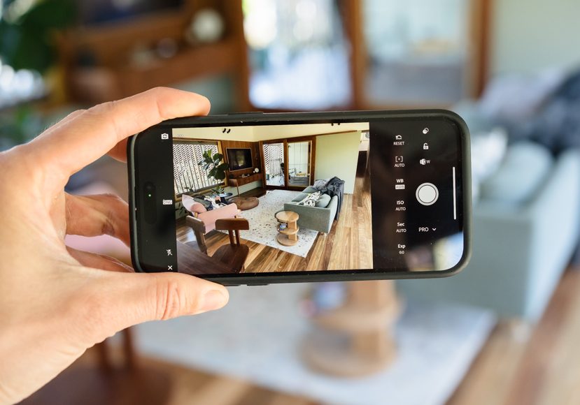A person taking a photo of a living room with a smartphone.