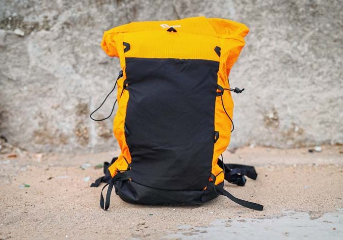 An orange and black backpack sitting on the ground.