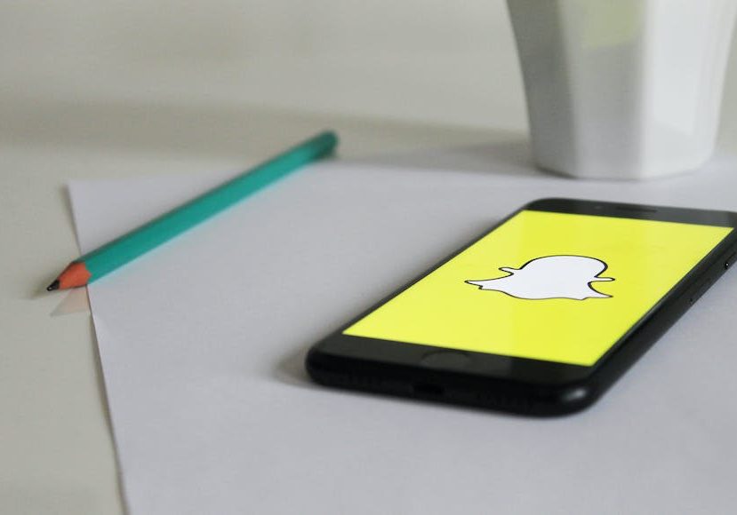 A phone with a snapchat logo on it sits on a table.
