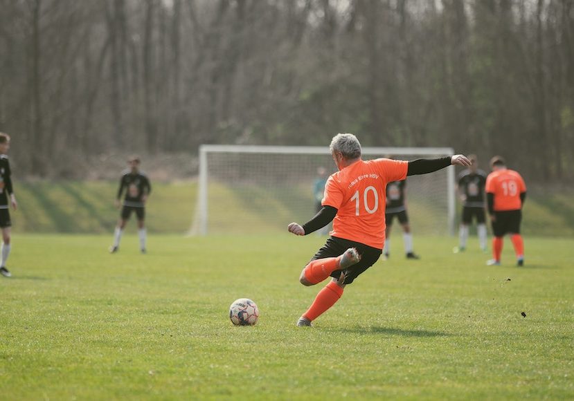 A man is kicking a soccer ball on a field.
