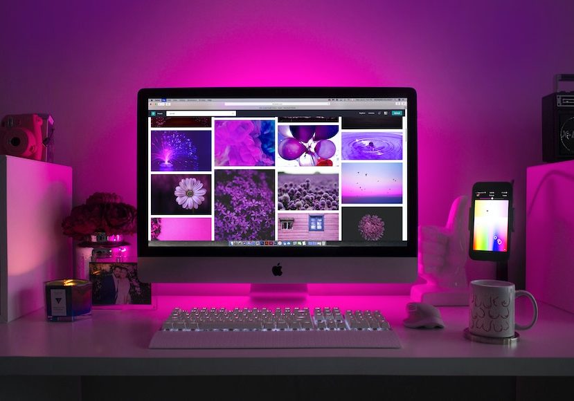 A desk with a monitor, keyboard, mouse, and a lamp.