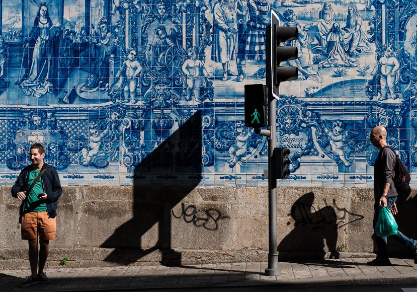 a man walking down a sidewalk next to a blue wall.