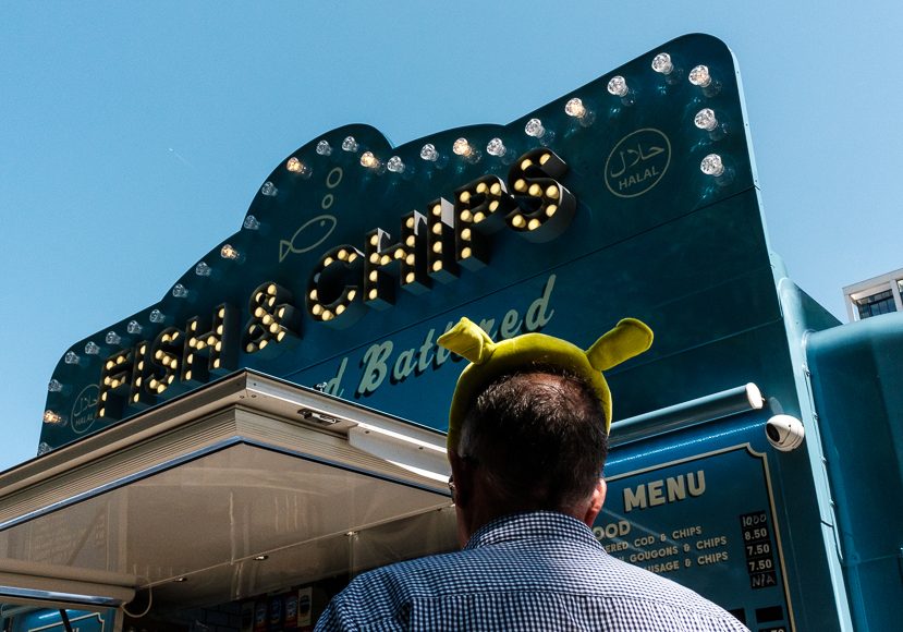 a man wearing a pikachu hat in front of a restaurant.